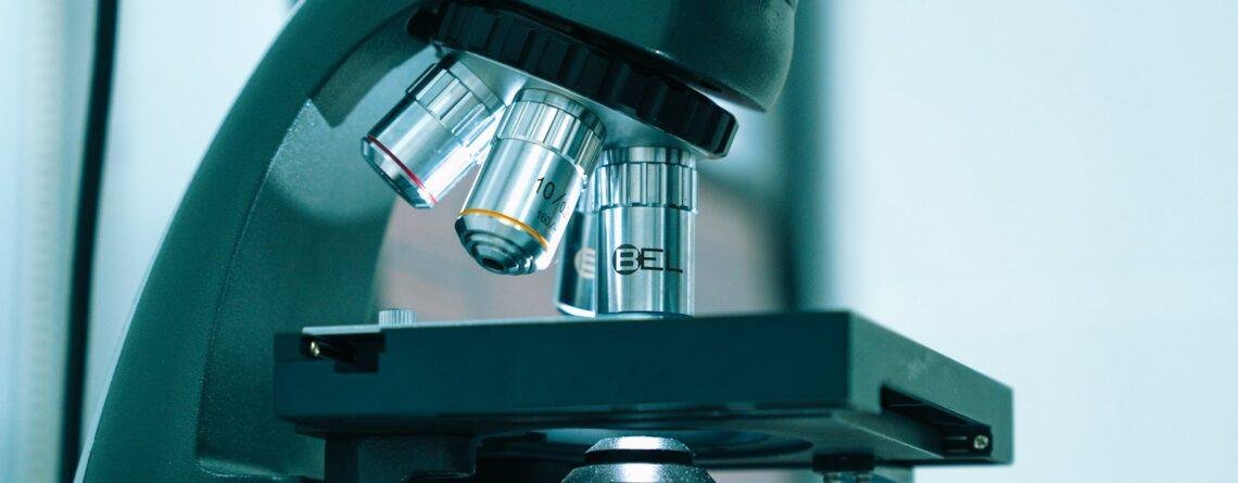 Gloved hand operating a microscope in a laboratory